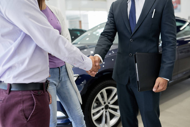 Skadrowana sprzedawca gratulacji klientów na zakup nowego samochodu, drżenie rąk - Zdjęcie, obraz