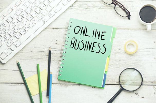 online business text on notepad with pencils, computer keyboard, eyeglasses and coffee cup on white wooden table - Foto, immagini