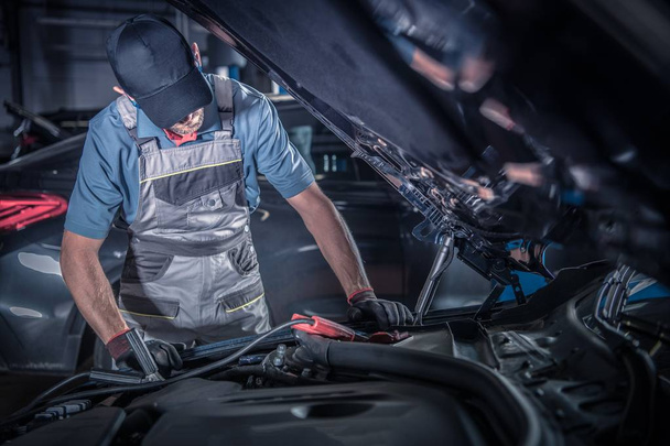 Car Mechanic Work. Caucasian Vehicles Technician Looking Under Car Hood Looking For the Existing Problem. Automotive Industry - Foto, Imagen