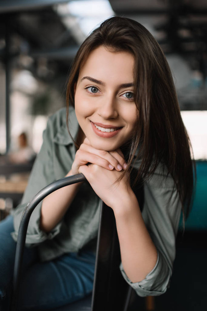 Közelkép portré vidám mosolygós nő ül a modern kávézóban. Fiatal gyönyörű és pozitív nő pózol képeket beltérben - Fotó, kép