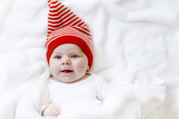 Cute adorable baby child with Christmas winter cap on white background. Happy baby girl or boy smiling and looking at the camera. Close-up for xmas holiday and family concept - 写真・画像
