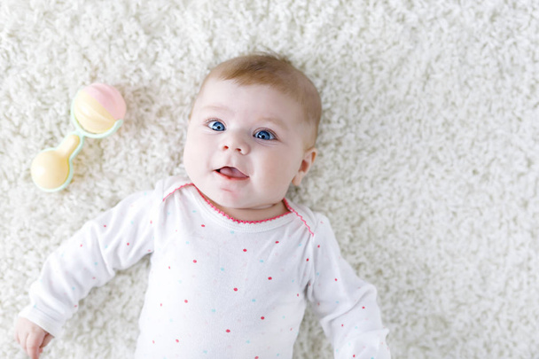 Cute adorable newborn baby playing with colorful pastel vintage rattle toy. New born child, little girl looking at the camera. Family, new life, childhood, beginning concept. Baby learning grab. - Photo, image