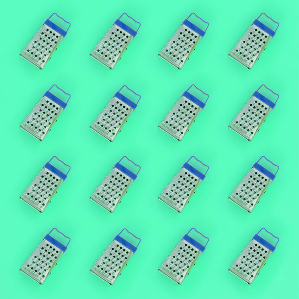 Small stainless steel graters lies on a pastel colored paper. Kitchen accessories. Tools for cooking. Flat lay top view - Photo, Image