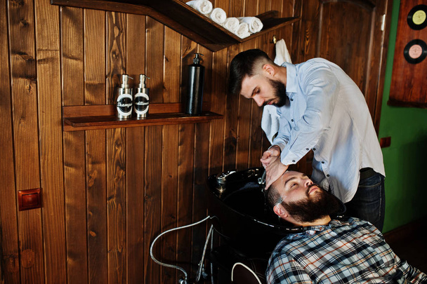 Handsome bearded man at the barbershop, barber at work. Washing head. - Photo, image