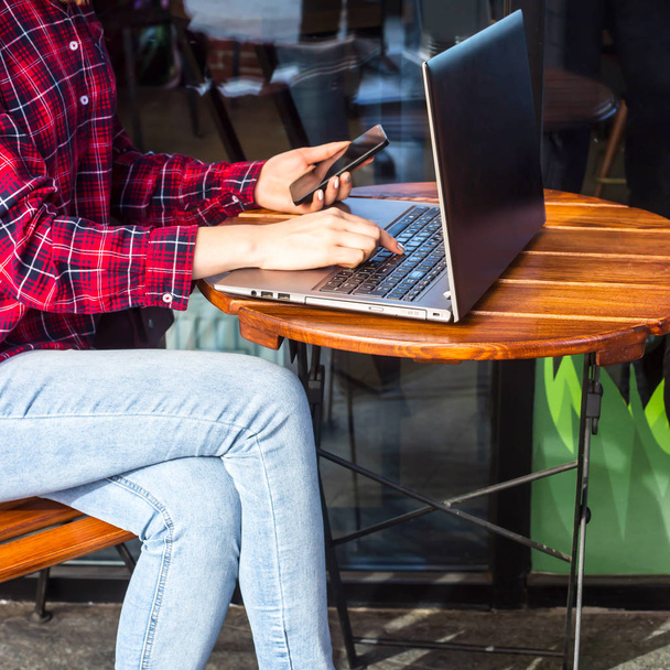 Das Mädchen arbeitet hinter einem Laptop an einem Tisch in einem Café neben einer Tasse Kaffee in einer Basteltasse. Arbeitskonzept für Freiberufler - Foto, Bild