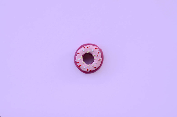 Único pequeno donut de plástico encontra-se em um fundo colorido pastel. Plana leigos composição mínima. Vista superior
. - Foto, Imagem