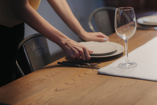 Unrecognsisable young woman setting up table for dinner party at home. - Foto, afbeelding