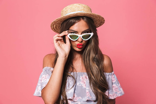 Portrait of a seductive young girl in summer clothes looking at camera over pink background - Foto, Imagem