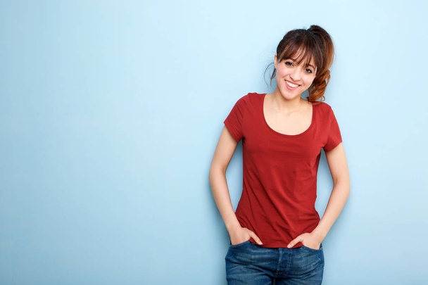 Портрет молодой женщины, улыбающейся у голубой стены
 - Фото, изображение