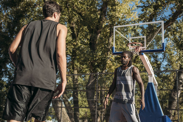 Two man playing basketball at outdoor court. - Foto, afbeelding