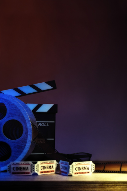 Apparatuur en onderdelen van bioscoop op houten tafel en donker blauwe achtergrond. Concept van het bekijken van films. Verticale compositie. Vooraanzicht. - Foto, afbeelding