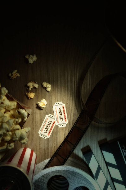 Vintage equipment and elements of cinema on wooden table. Concept of watching movies. Vertical composition. Top view. - Photo, image