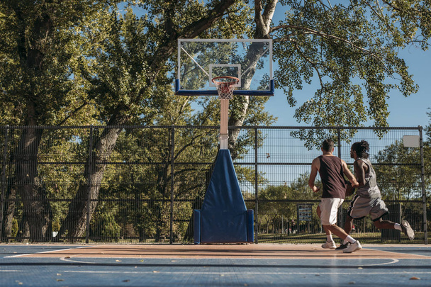 Два красивых мужчины играют в баскетбол на открытом воздухе
. - Фото, изображение