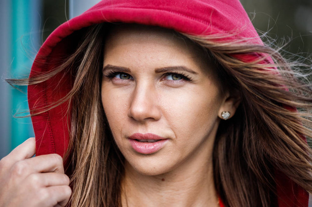 Closeup portrait of beautiful young woman wearing red swimsuit and red hoodie, blurred background - Foto, Imagen