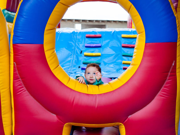 Cute toddler reaching out from trampoline castle - Photo, Image