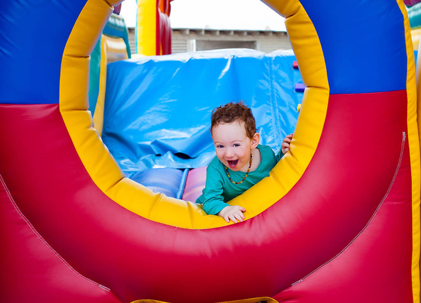 Laughing adorable little kid climbs trampoline castle - Photo, Image