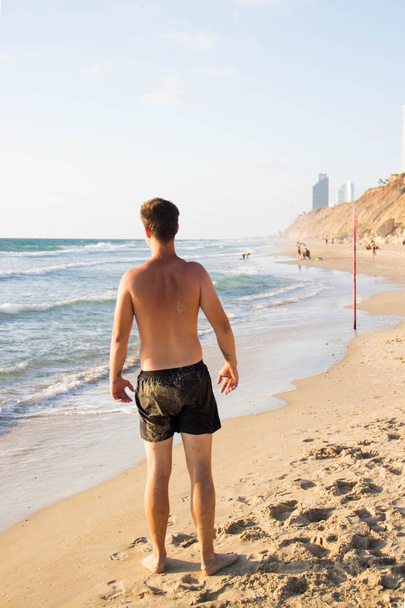 Young attractive michina from the back against the sea with a naked back - Foto, afbeelding