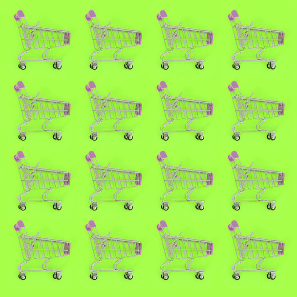 Shopping addiction, shopping lover or shopaholic concept. Many small empty shopping carts perform a pattern on a pastel colored paper background. Flat lay composition, top view - Fotoğraf, Görsel