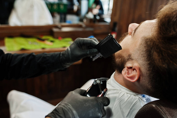 Handsome bearded man at the barbershop, barber at work. - 写真・画像