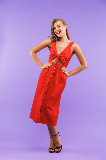Full length portrait of caucasian cute woman 20s wearing red dress smiling at camera standing isolated over violet background - Fotografie, Obrázek