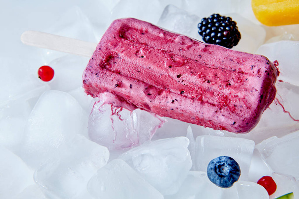Homemade vegan frozen beet popsicle over the ice with berries , flat lay. Summer dessert. - Photo, Image