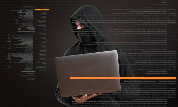 Hacker con su ordenador mirando lateral sobre fondo oscuro
 - Foto, imagen