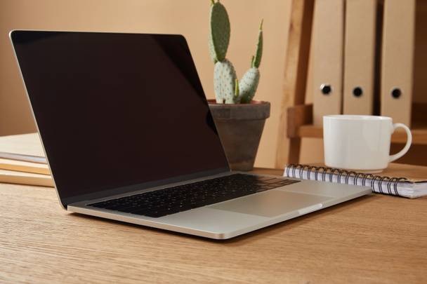 laptop met leeg scherm en kopje koffie aan tafel  - Foto, afbeelding