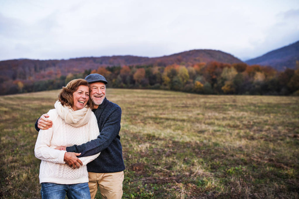 Senior couple hugging in an autumn nature at sunset, laughing. - Foto, immagini