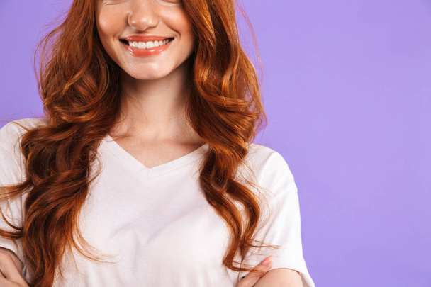 Cropped image of a smiling young girl standing isolated over violet background, wearing blank t-shirt - Фото, зображення