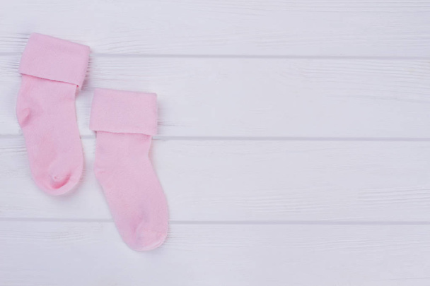 Pink pair of baby socks with copy space. White wood background. - Fotografie, Obrázek