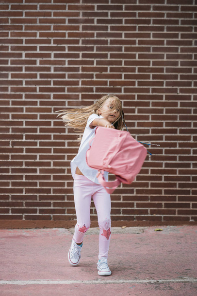 Χαριτωμένο μαθήτρια παίζει με τη σακούλα σε ένα δρόμο - Φωτογραφία, εικόνα