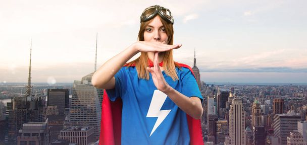 Bastante chica superhéroe haciendo tiempo fuera gesto en una ciudad rascacielos
 - Foto, imagen