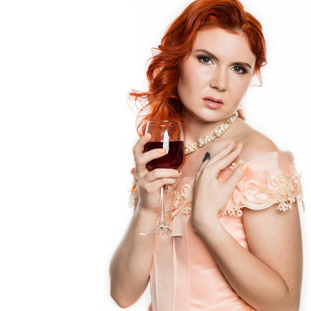 Young redhead woman drinks a red wine with a happy face and smiling with a confident smile. white background. free space for your text - Fotó, kép
