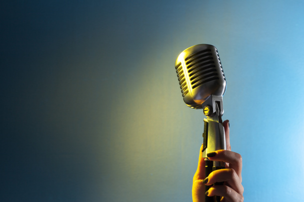 Γυναίκα τραγουδίστρια χέρι με μικρόφωνο σε στυλ ρετρό  - Φωτογραφία, εικόνα