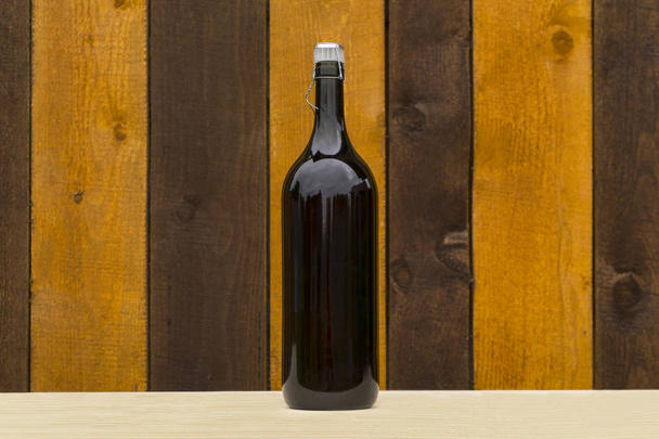 verkorkte Flasche dunkles Glas mit Hauswein steht auf einem Regal vor dem Hintergrund einer Holzwand - Foto, Bild
