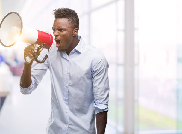 Young african american man holding megaphone annoyed and frustrated shouting with anger, crazy and yelling with raised hand, anger concept - Photo, Image