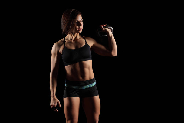 jovem muscular esportes menina envolvida com peso em um fundo preto
 - Foto, Imagem