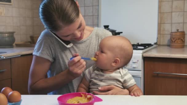 Little child eating puree and watching baby app on smartphone. - Imágenes, Vídeo