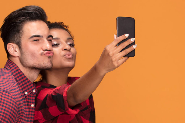 Mixed raced couple of students taking selfie with mobile phone at studio. - Photo, image