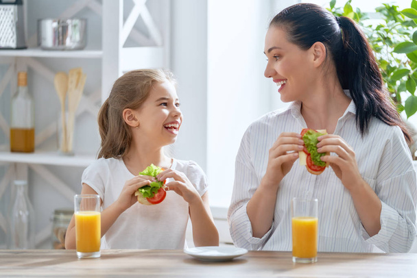 Healthy food at home. Happy family in the kitchen. Mother and child daughter are having breakfast. - Foto, afbeelding
