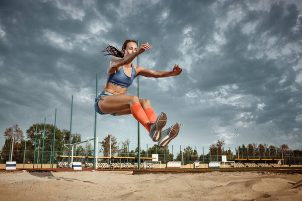 Female athlete performing a long jump during a competition - Foto, Imagem