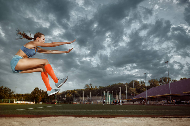 Female athlete performing a long jump during a competition - Foto, Bild