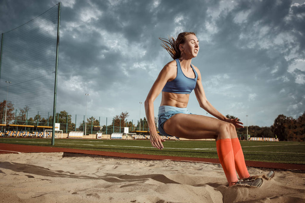 Female athlete performing a long jump during a competition - Foto, Bild