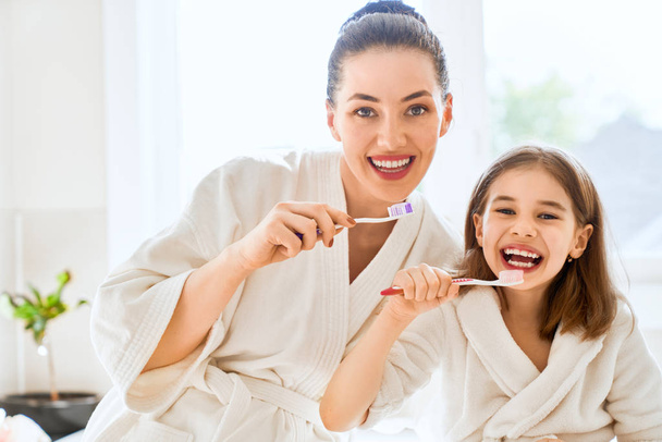 Happy family! Mother and daughter child girl are brushing teeth toothbrushes in the bathroom. - Foto, imagen