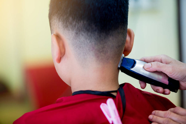 Friseurladen. Friseur frisiert einen asiatischen Jungen mit Haarschneidemaschine. modischer Haarschnitt für Jungen. - Foto, Bild
