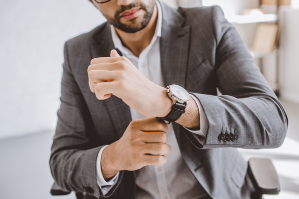 cropped image of businessman wearing wristwatch in office - Фото, изображение