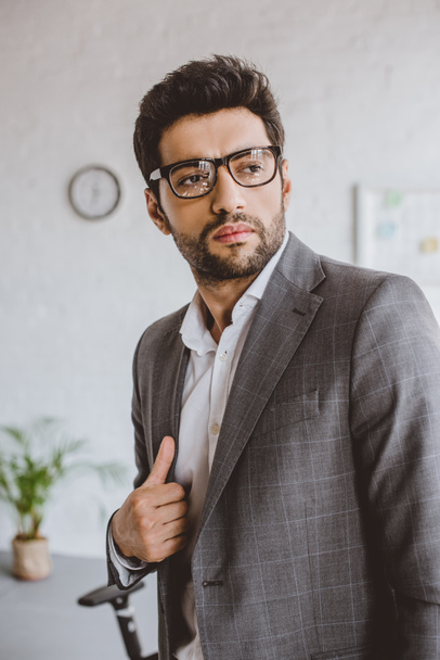 handsome businessman in glasses looking away in office - Zdjęcie, obraz