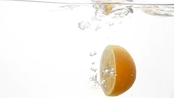 Closeup slow-motion beelden van tropic citrusvruchten helften vallen en spetteren in het koude heldere water - Video