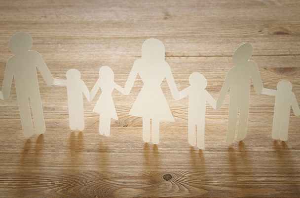 concept image of Family paper chain cutout holding hands, over wooden table - Fotó, kép