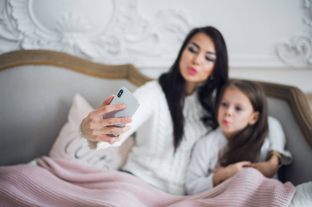 Happy mother and daughter taking funny Christmas selfies at home - Photo, Image